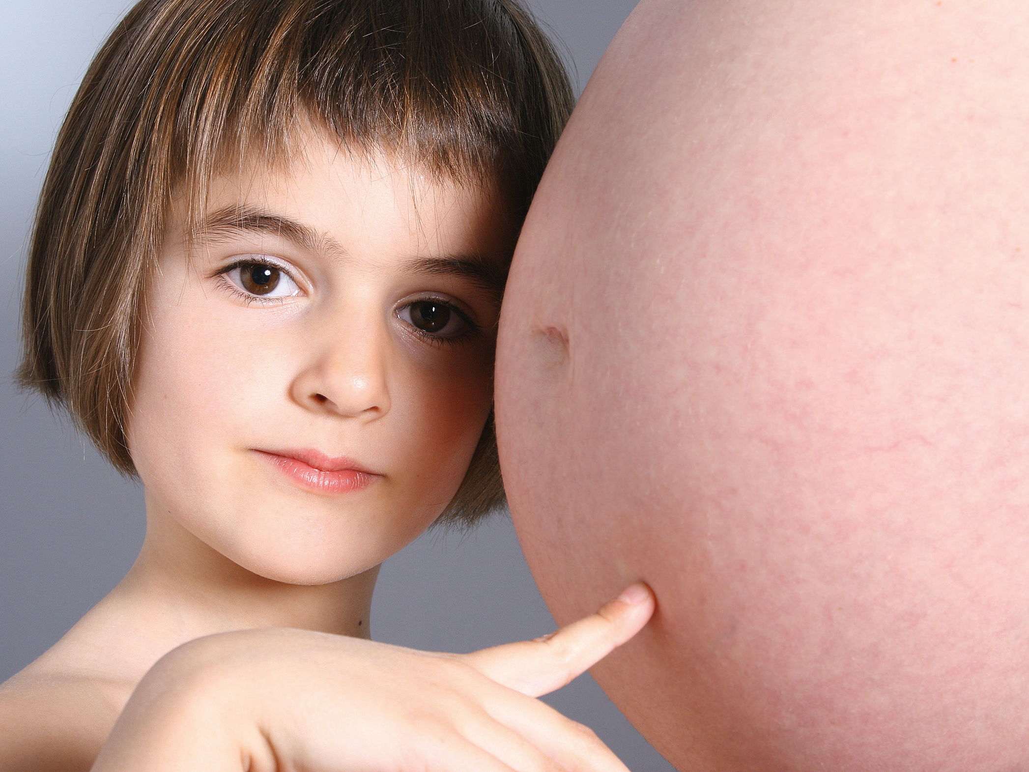Kind berührt den Babybauch der Mutter