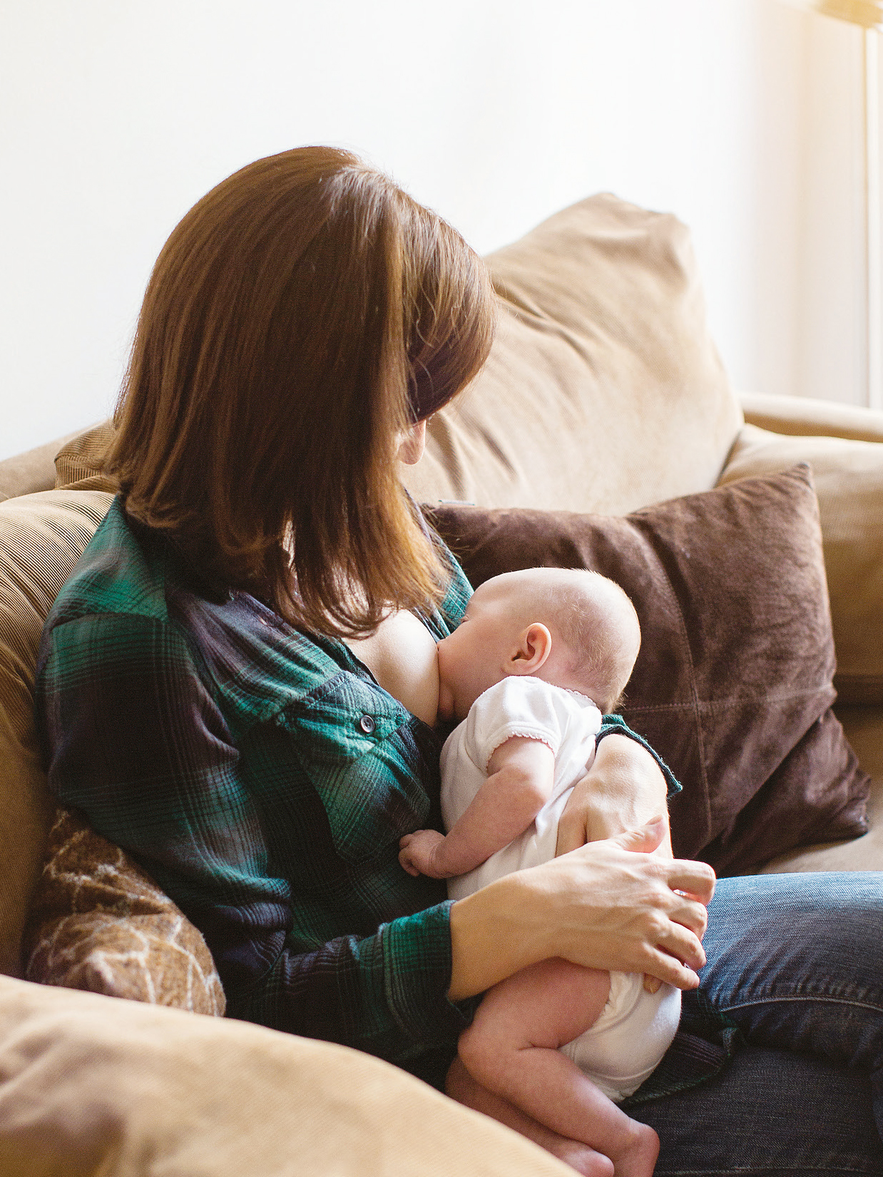 Mutter stillt Baby auf dem Sofa