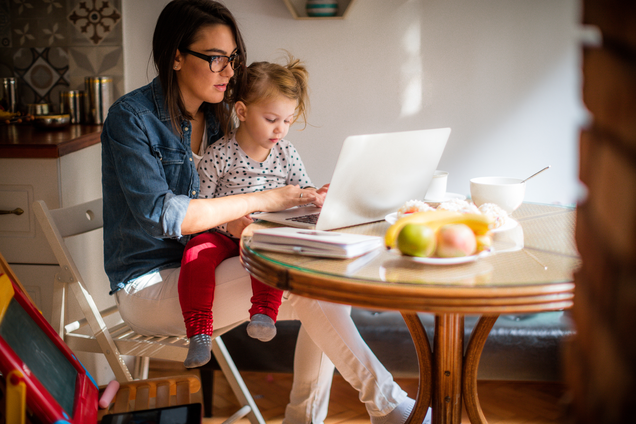 Mutter mit Kleinkind auf dem Schoss am Laptop