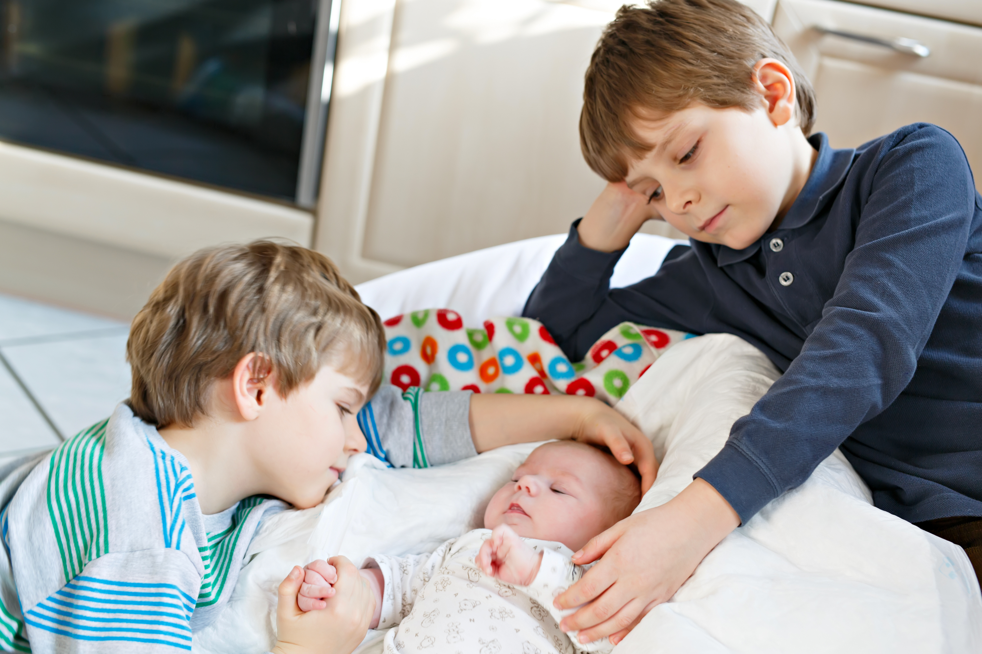 Zwei Brüder knuddeln mit Baby