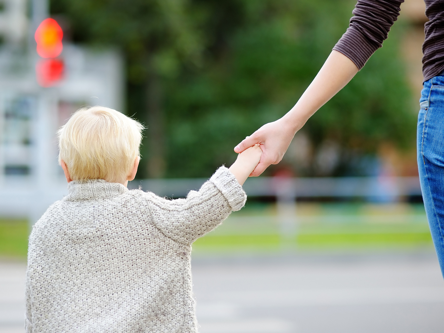 Junge an Hand von Mutter wartend vor dem Rotlicht