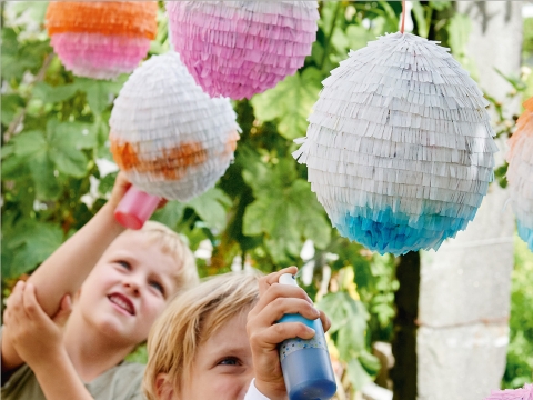 Zwei Knaben besprayen Eier-Piñatas